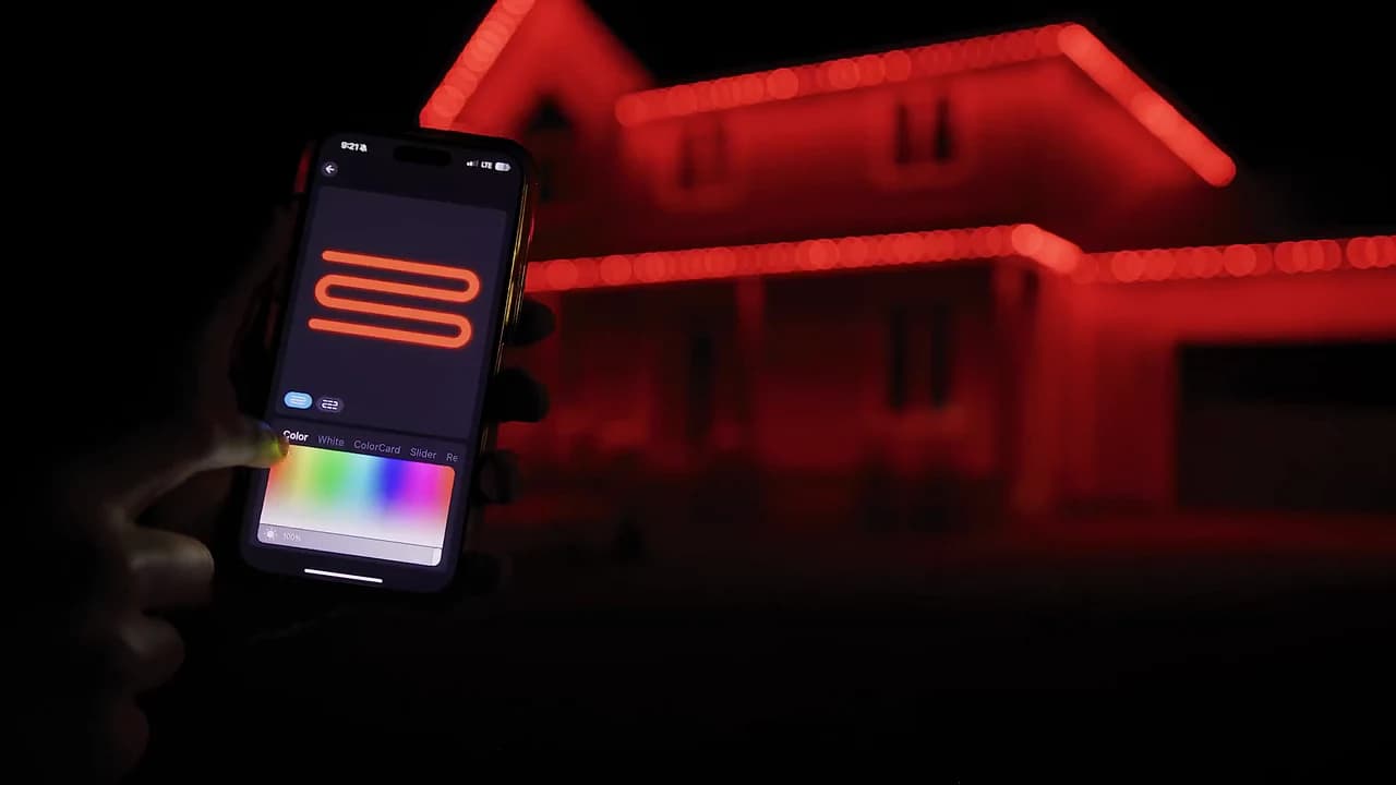 L’application Luminov sur un téléphone, devant une maison illuminée